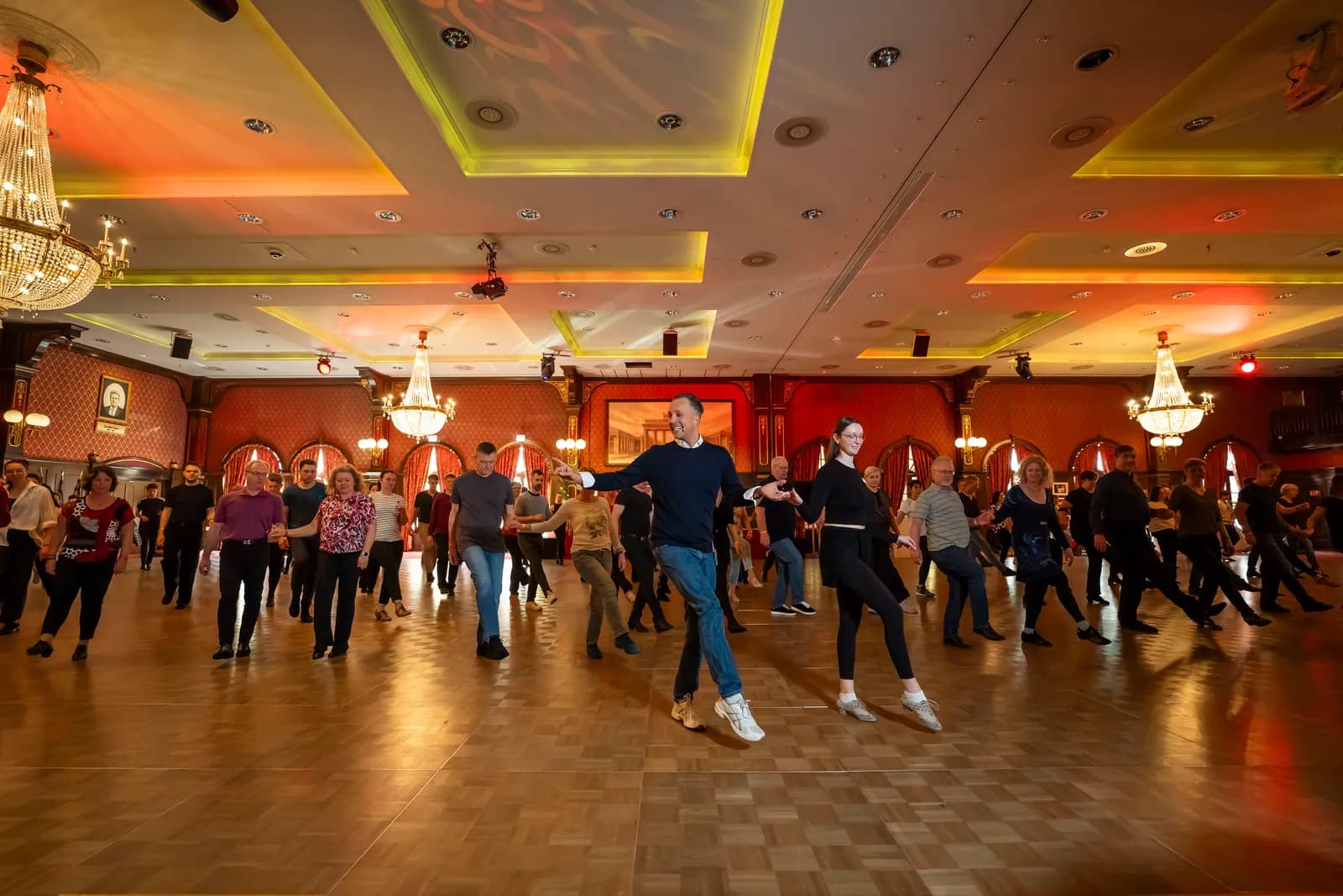 Voller Ballsaal beim Trainingslager: viele Paare tanzen gemeinsam, Roman Frieling führt in der Mitte vor.